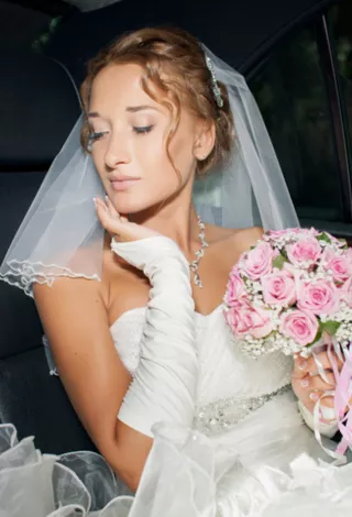 A bride holding flowers while sitting in a limo