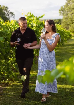 A beautiful couple taking a walk in the vineyard while drinking wine