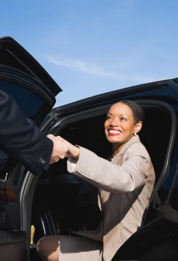 Chauffeur helping a business woman to get out of car at airport