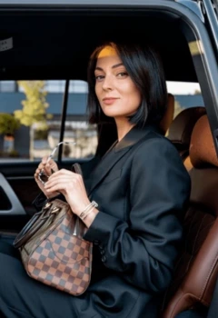 A woman sitting in a luxury black SUV holding her purse