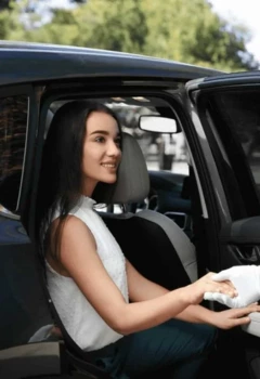 Chauffeur helping a woman to get out of a luxury black sedan